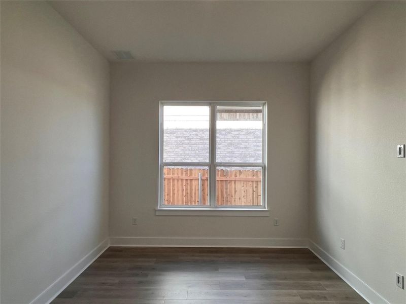 Empty room featuring dark wood-style flooring and baseboards