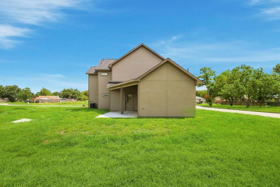 Charming two-story home with a spacious, lush green lawn and a cozy covered patio, perfect for outdoor enjoyment.