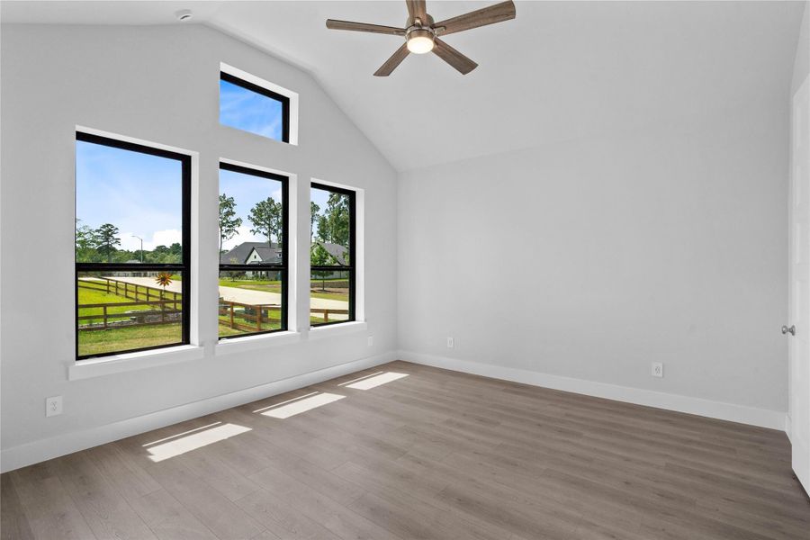 Relax and unwind after a long day in this impressive primary suite! This generously sized room offers LVP flooring, neutral-toned paint, high ceilings with a ceiling fan, and large windows for added comfort and tranquility.