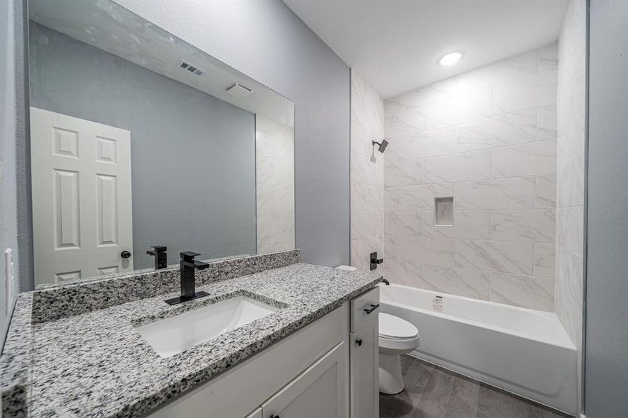 Bathroom featuring bathing tub / shower combination, vanity, and dark wood-style floors Bathroom featuring bathing tub / shower combination, vanity, and dark wood-style floors