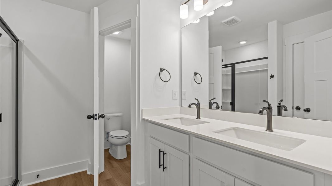 Notable primary bath featuring dual vanity, walk-in shower, and tasteful design touches throughout