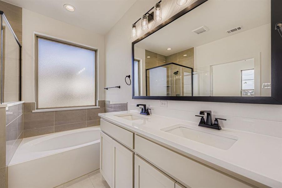 Full bathroom with double vanity, a bath, a stall shower, light tile patterned floors, and recessed lighting Full bathroom with double vanity, a bath, a stall shower, light tile patterned floors, and recessed lighting
