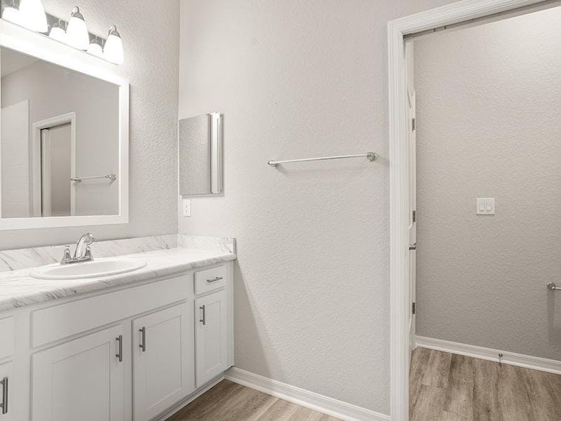 The bedroom 2 suite includes a large single-vanity en-suite bath with a private toilet and linen closet - Everly by Highland Homes
