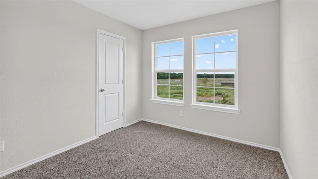 Room featuring two windows with white frames, providing natural light and a field scenery Room featuring two windows with white frames, providing natural light and a field scenery