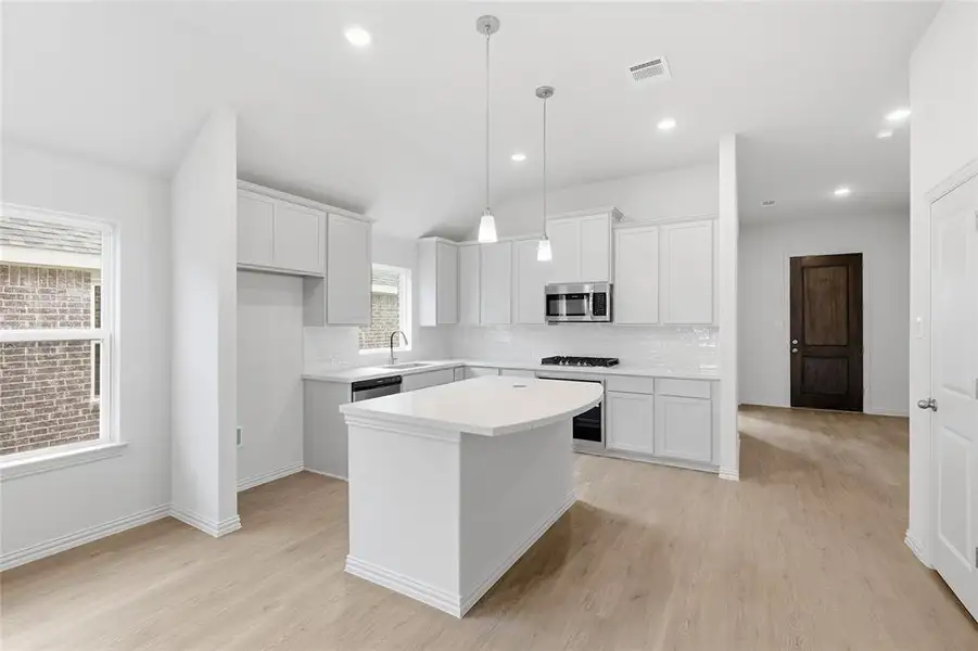 Kitchen with a kitchen island, light wood-type flooring, white cabinets, and lofted ceiling
