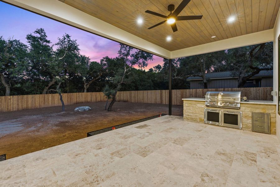 A spacious covered patio features tiled flooring, wood ceilings, and an outdoor kitchen setup.