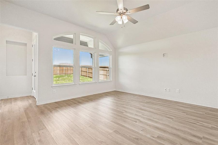 Spare room with light hardwood / wood-style floors, lofted ceiling, and ceiling fan