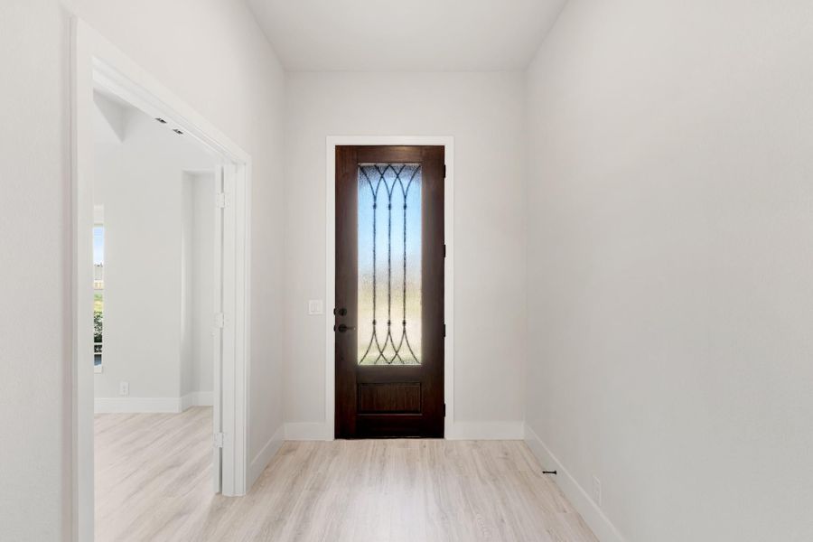 Entryway with dark wood front door featuring decorative glass panel and light hardwood floors