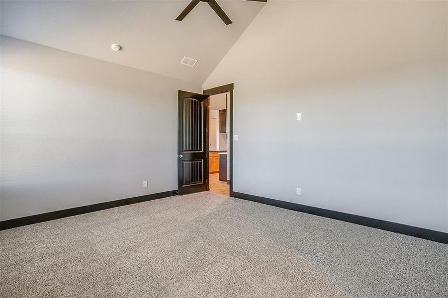 Carpeted empty room featuring high vaulted ceiling and ceiling fan