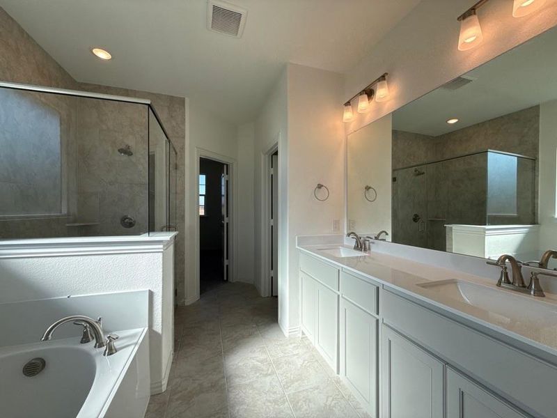 Full bathroom with double vanity, a garden tub, and a stall shower