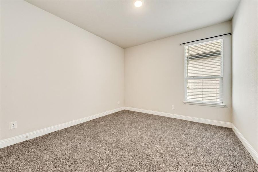Carpeted spare room featuring baseboards