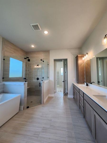 Spacious bathroom featuring a freestanding tub, glass-enclosed shower with bench, dual vanity with undermount sinks, and large format tile flooring