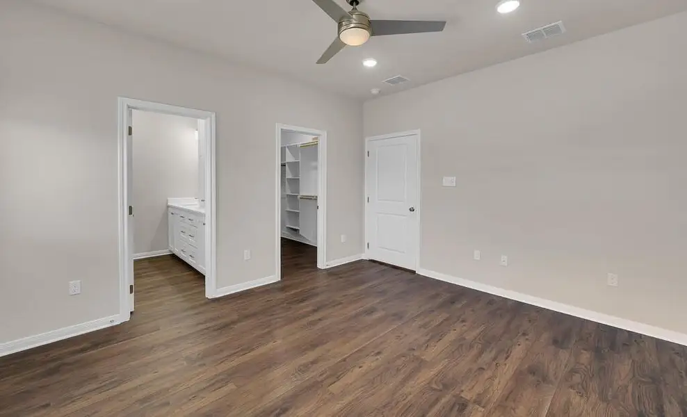 Unfurnished bedroom featuring a spacious closet, dark wood finished floors, a closet, ceiling fan, and recessed lighting