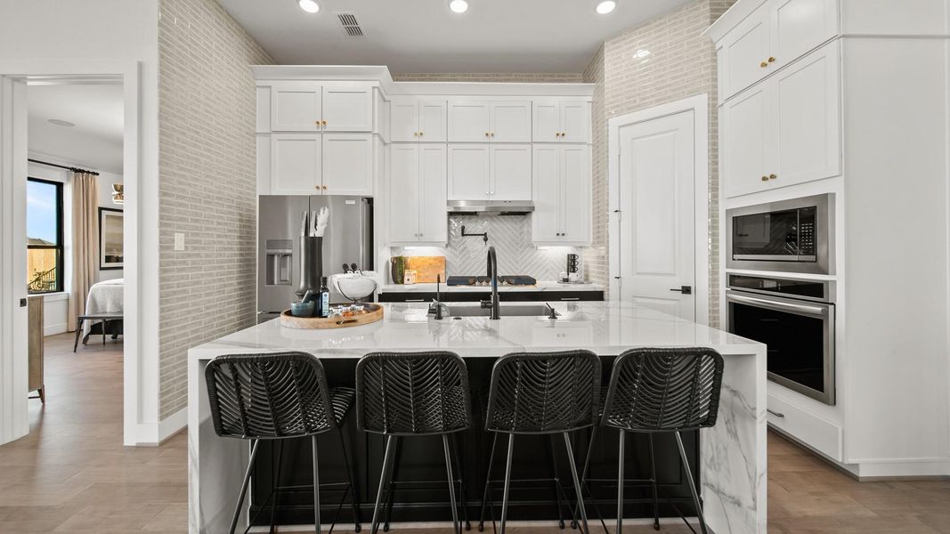This prestigious kitchen shows off with modern two-toned cabinetry stacked to the ceiling. Uniquely tiled walls to match the attractive backsplash meet attractive porcelain waterfall style countertops. This prestigious kitchen shows off with modern two-toned cabinetry stacked to the ceiling. Uniquely tiled walls to match the attractive backsplash meet attractive porcelain waterfall style countertops.