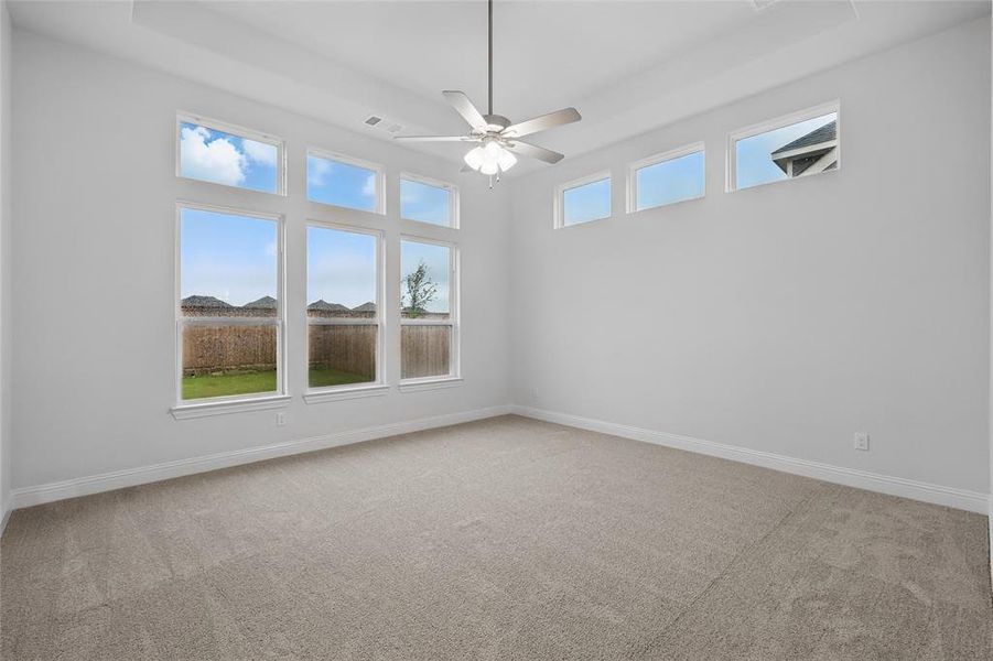 Carpeted spare room with ceiling fan and baseboards