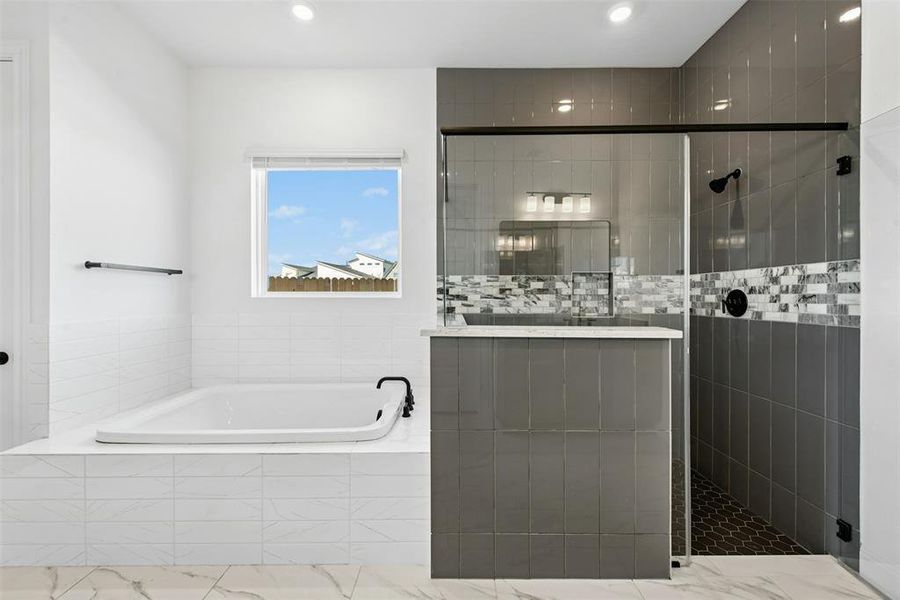 Contemporary bathroom featuring a large soaking tub with matte black fixtures, a separate walk-in shower with glass enclosure, gray subway tile, and a decorative mosaic accent band