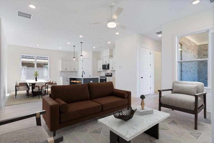 Open-concept interior featuring wood-finish flooring, recessed lighting, a center kitchen island, and white shaker-style cabinetry Open-concept interior featuring wood-finish flooring, recessed lighting, a center kitchen island, and white shaker-style cabinetry