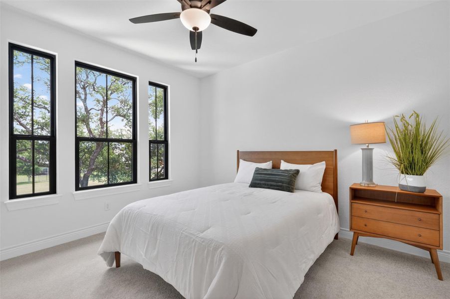 Sun-filled bedroom featuring multiple tall windows and a ceiling fan for comfort. Sun-filled bedroom featuring multiple tall windows and a ceiling fan for comfort.