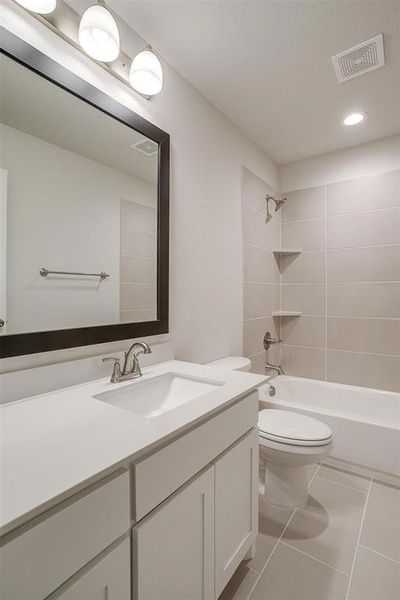 Full bathroom with tile patterned flooring, toilet, tiled shower / bath combo, and vanity