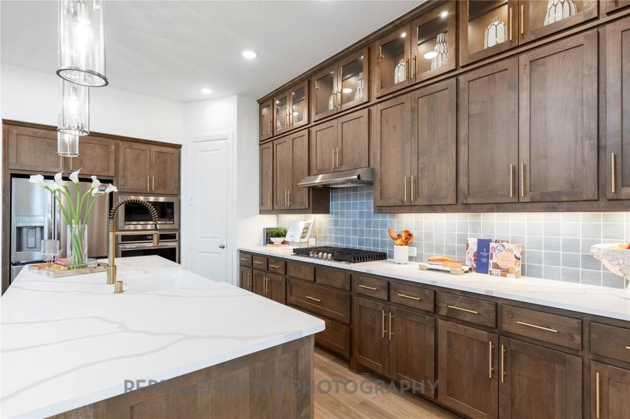 Kitchen featuring light wood-style floors, backsplash, pendant lighting, appliances with stainless steel finishes, and recessed lighting