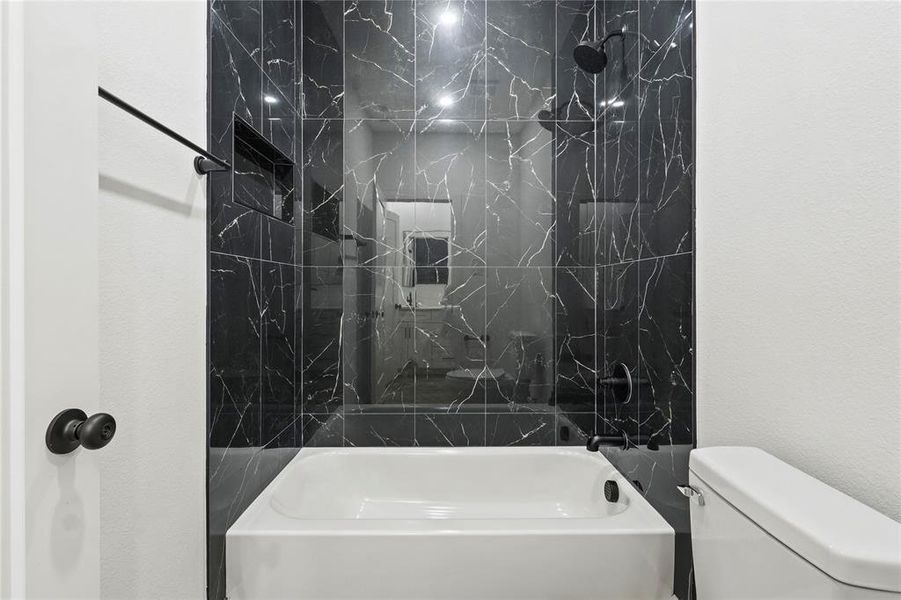 Bathroom featuring shower / bath combination and a textured wall