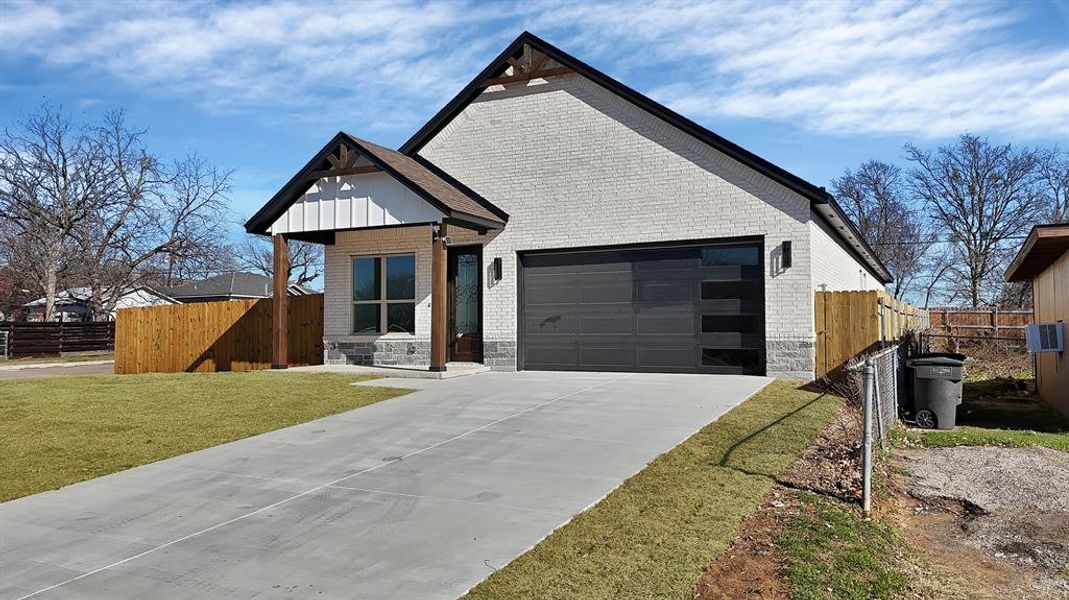 View of front of home featuring brick siding, concrete driveway, and a garage