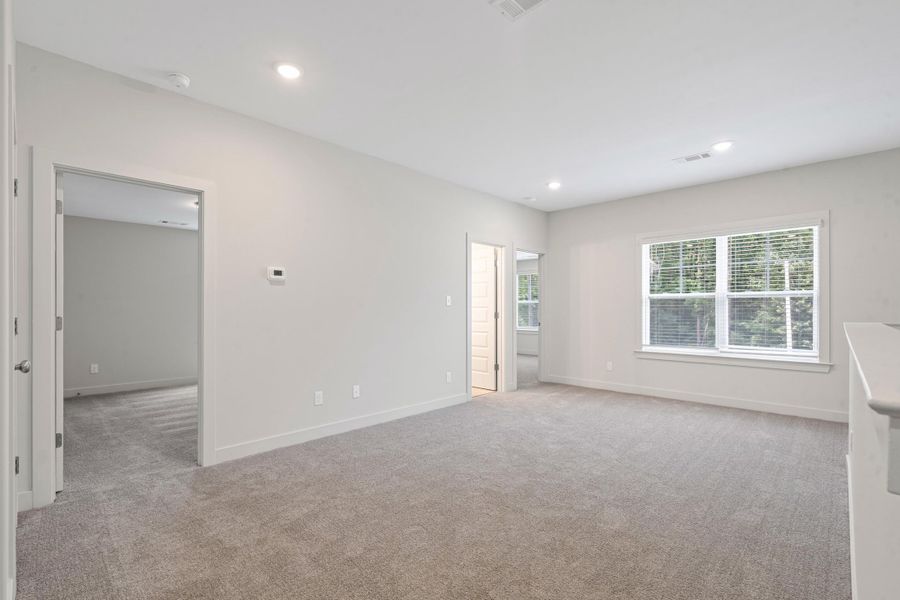 Spacious room with plush carpeting, recessed lighting, white trim, a large window, and light gray walls Spacious room with plush carpeting, recessed lighting, white trim, a large window, and light gray walls
