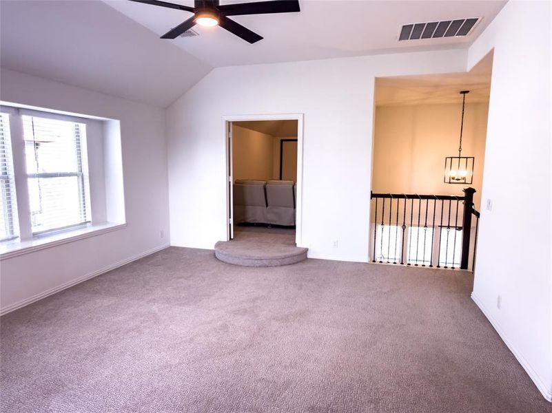 Spare room with ceiling fan, vaulted ceiling, and carpet