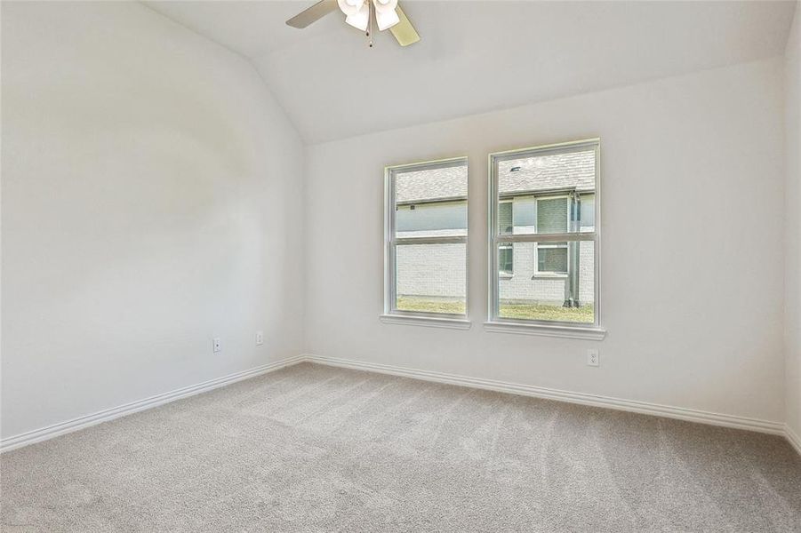 Carpeted empty room with lofted ceiling and ceiling fan