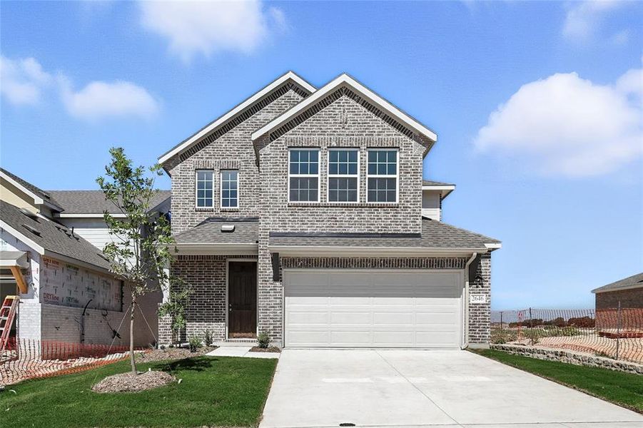 Traditional home with driveway, roof with shingles, brick siding, and an attached garage Traditional home with driveway, roof with shingles, brick siding, and an attached garage
