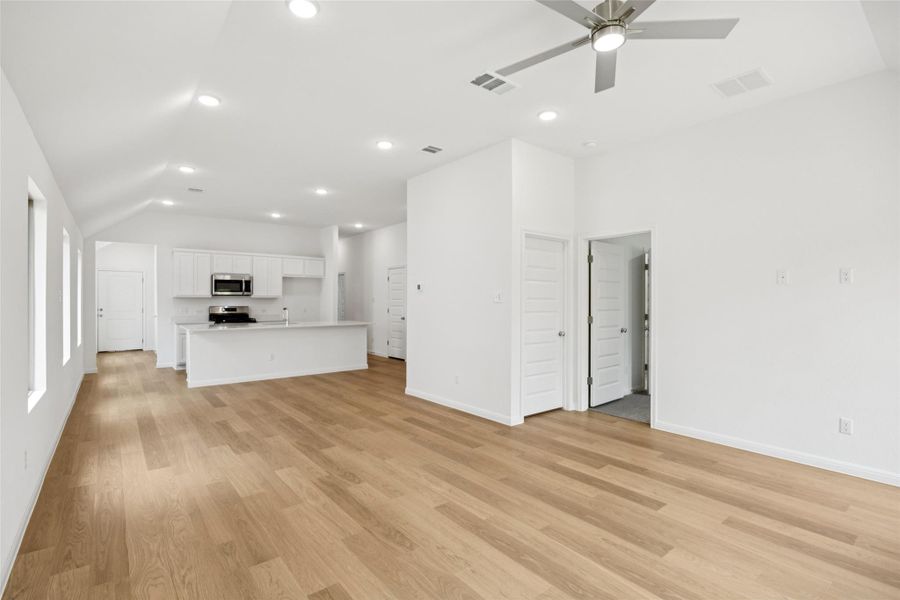 Unfurnished living room with light wood finished floors, vaulted ceiling, recessed lighting, and a ceiling fan Unfurnished living room with light wood finished floors, vaulted ceiling, recessed lighting, and a ceiling fan
