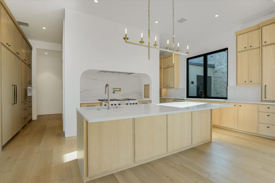 Kitchen with light wood finish cabinetry, modern cabinets, light wood-style floors, and decorative light fixtures