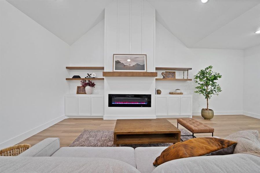 Living room featuring a vaulted ceiling, wood-finish flooring, and recessed lighting Living room featuring a vaulted ceiling, wood-finish flooring, and recessed lighting