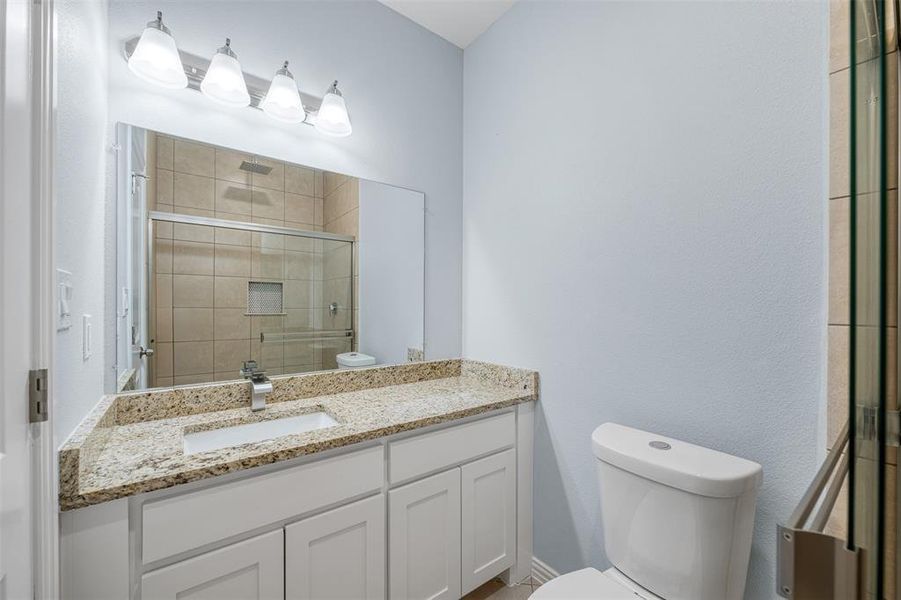 Bathroom featuring vanity, toilet, and an enclosed shower