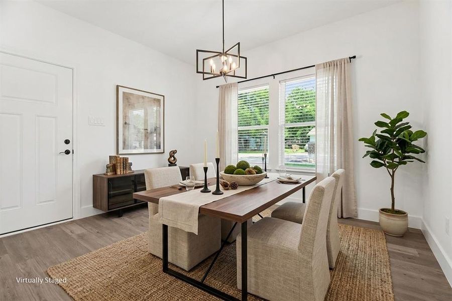 Dining area featuring wood-look flooring, a modern chandelier, and windows with blinds and sheer curtains