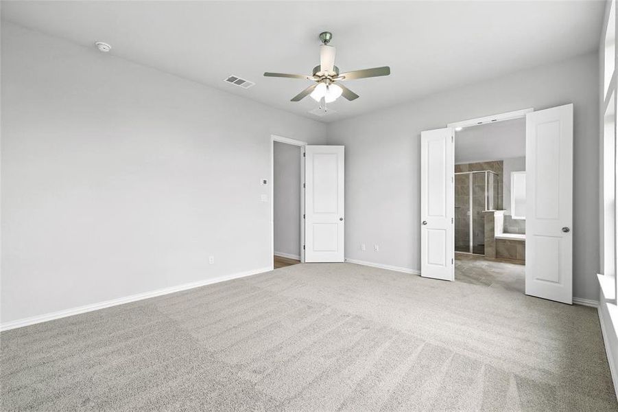 Unfurnished bedroom featuring light colored carpet, ceiling fan, and ensuite bath