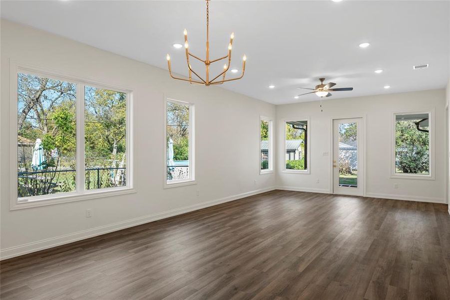 Unfurnished room with recessed lighting, dark wood-style floors, a chandelier, and ceiling fan Unfurnished room with recessed lighting, dark wood-style floors, a chandelier, and ceiling fan
