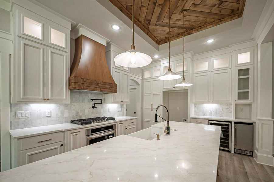 Kitchen with light stone counters, glass insert cabinets, pendant lighting, wooden ceiling, and recessed lighting Kitchen with light stone counters, glass insert cabinets, pendant lighting, wooden ceiling, and recessed lighting
