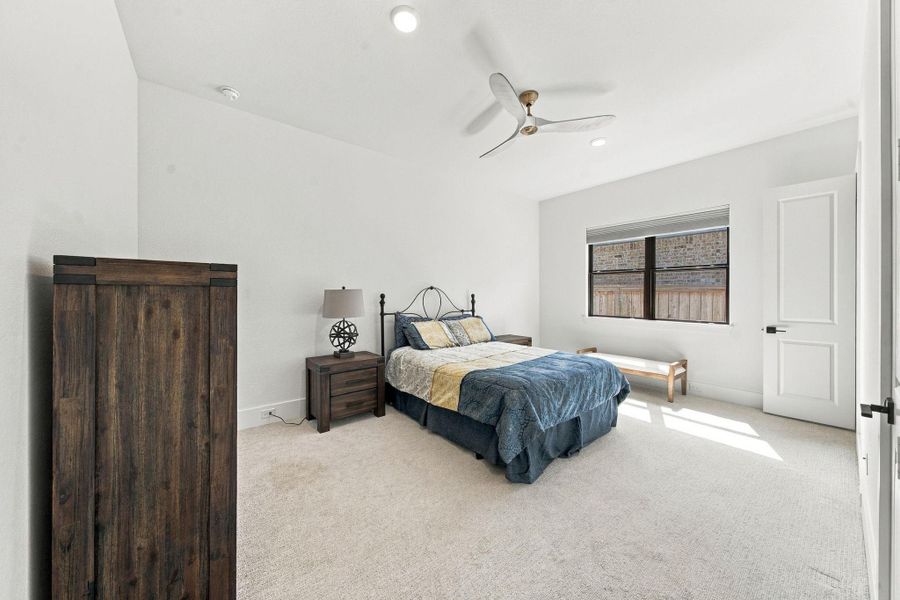 This third secondary bedroom offers a peaceful spot to unwind, featuring soft carpet flooring, a ceiling fan, and a window that brings in plenty of natural light.