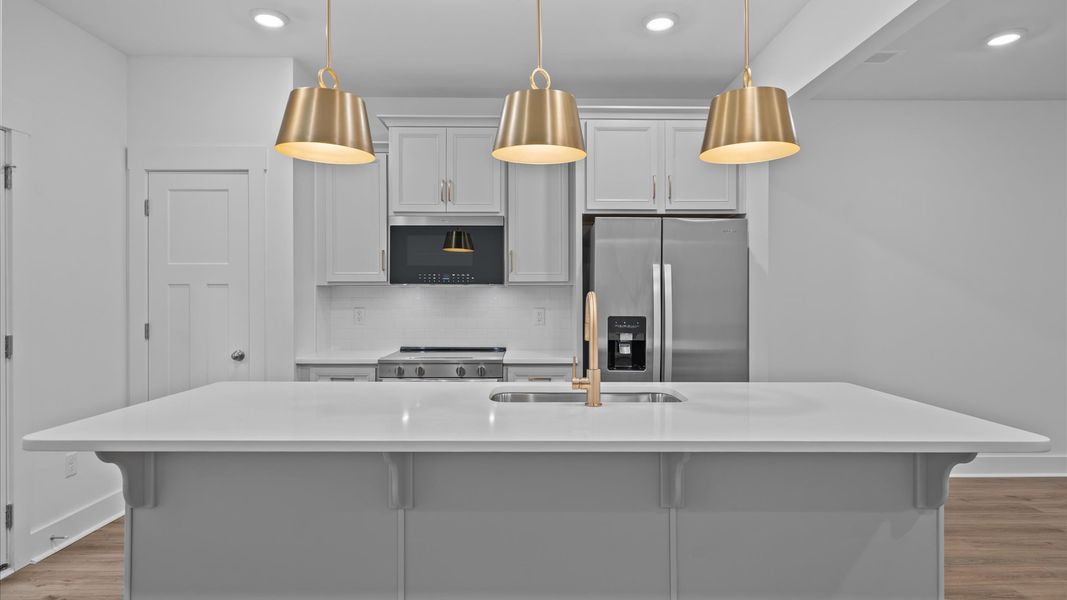 Tasteful design meets functional luxury in this kitchen with a 9-foot island and modern pendant lighting Tasteful design meets functional luxury in this kitchen with a 9-foot island and modern pendant lighting