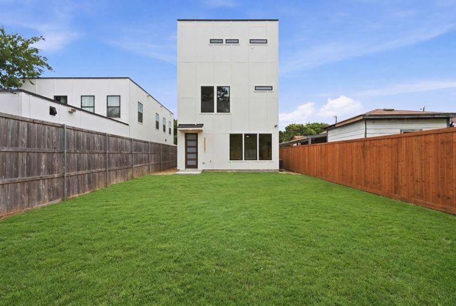 Modern vertical-sided white exterior featuring black-trimmed windows, a dark multi-pane entry door, and a spacious green lawn Modern vertical-sided white exterior featuring black-trimmed windows, a dark multi-pane entry door, and a spacious green lawn