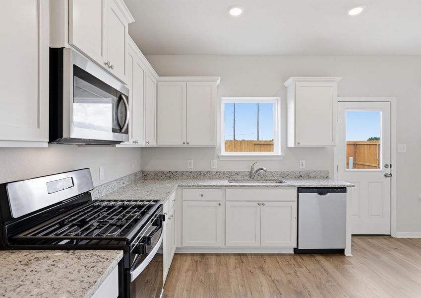 Kitchen detail featuring a stainless steel gas range, microwave, and dishwasher with granite countertops.