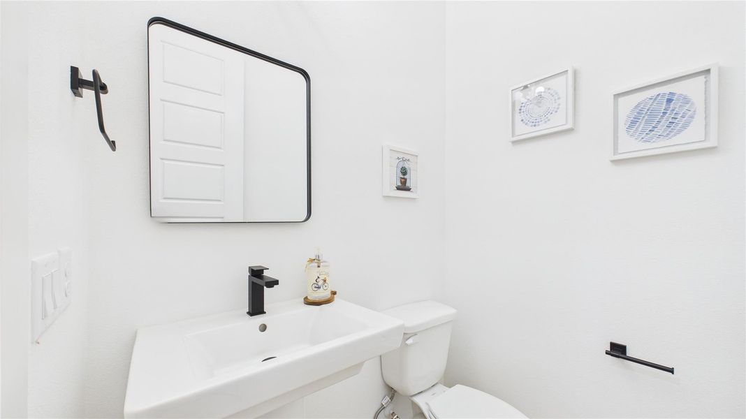Tucked conveniently near the living area, this powder room blends accessibility with sleek contemporary style. Clean lines and modern fixtures define the space, from the minimalist vanity to the streamlined sink and faucet.