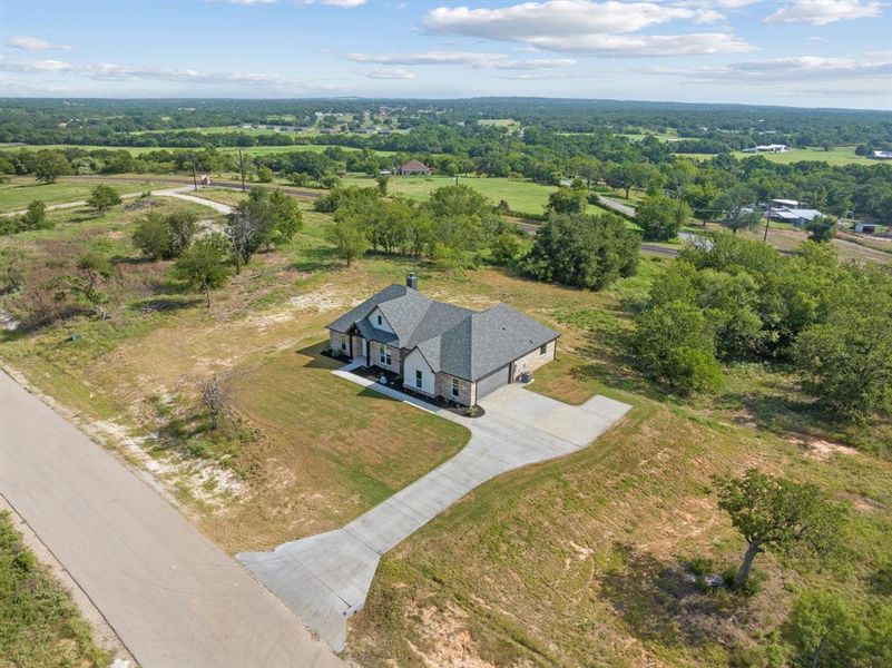 View of side of property with concrete driveway, brick siding, a shingled roof, and an attached garage