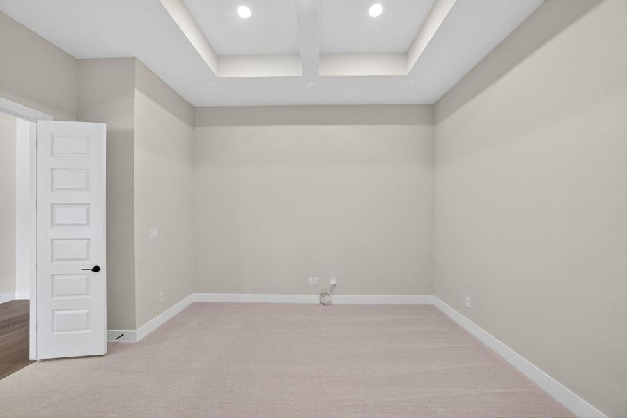 Empty room featuring light colored carpet and a tray ceiling Empty room featuring light colored carpet and a tray ceiling