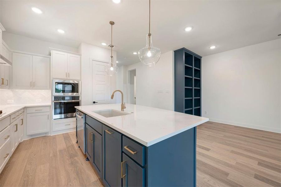The kitchen features light-colored cabinetry, stainless steel appliances, and a central island with a white countertop and dark blue base cabinetry