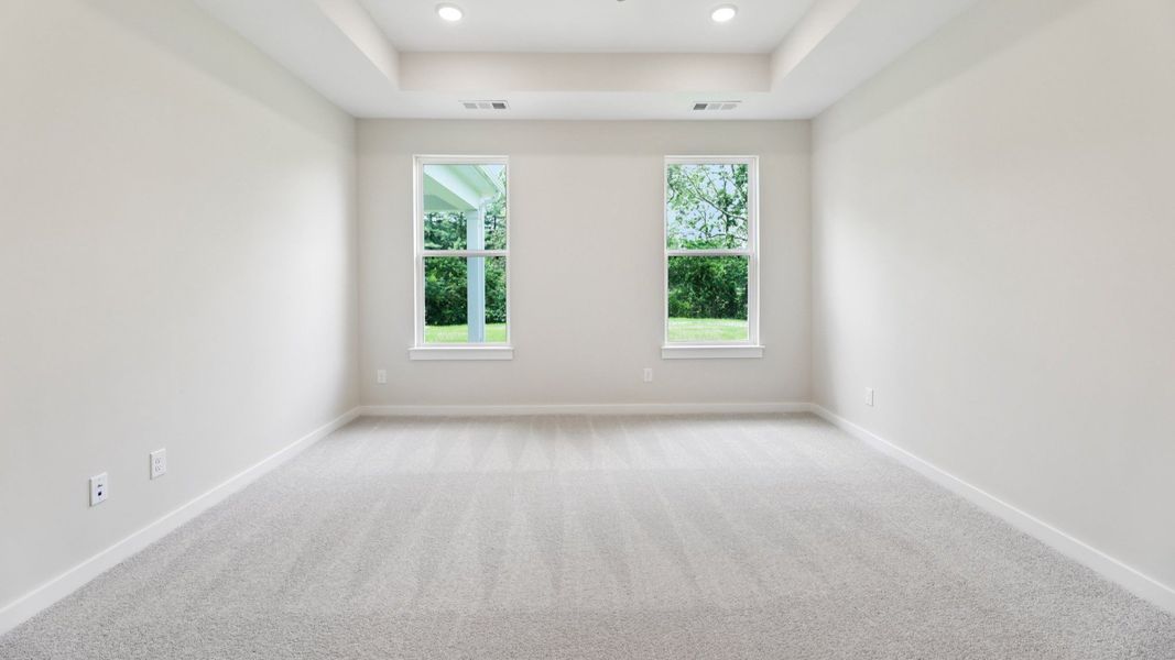 Primary Bedroom with tray ceiling and carpet