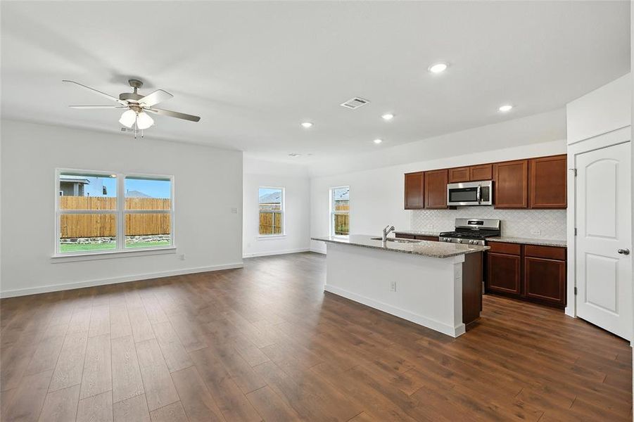 Kitchen with stainless steel appliances, open floor plan, dark wood-style flooring, recessed lighting, and a center island with sink Kitchen with stainless steel appliances, open floor plan, dark wood-style flooring, recessed lighting, and a center island with sink