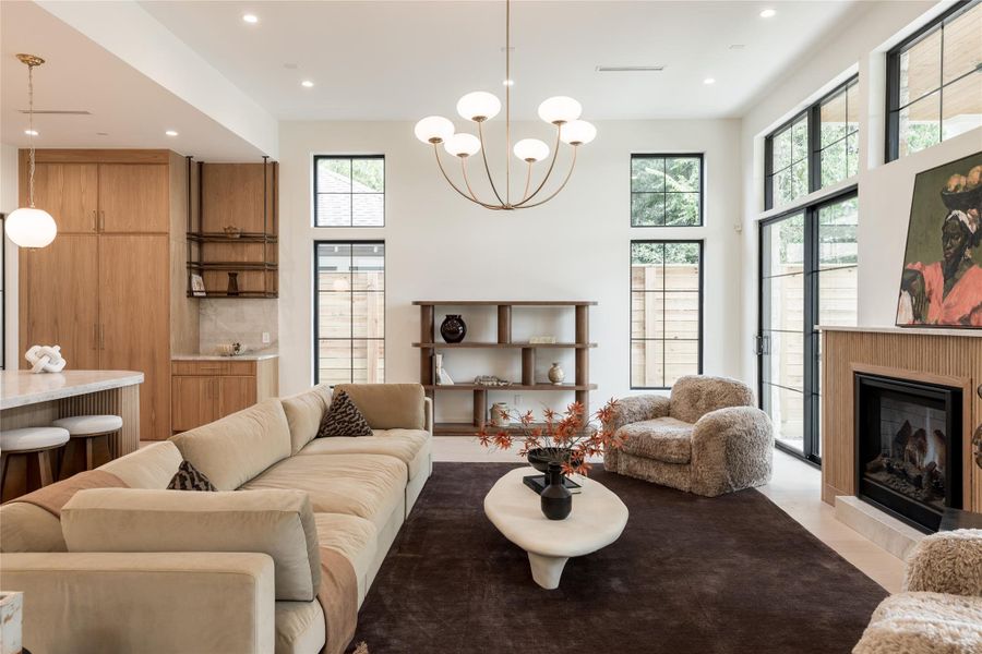 The great room balances dramatic scale with warmth, pairing 12 foot ceilings and a fluted fireplace with walls of grid windows that bring natural light deep into the space. The great room balances dramatic scale with warmth, pairing 12 foot ceilings and a fluted fireplace with walls of grid windows that bring natural light deep into the space.