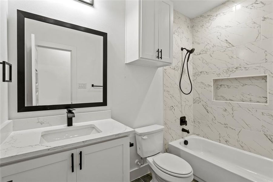 Full bathroom featuring vanity, toilet, and tiled shower / bath combo